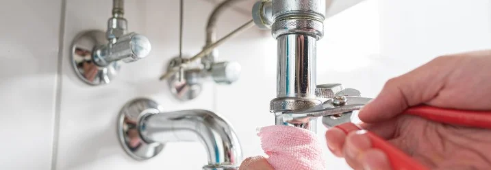 Person repariert Siphon mit Rohrzange